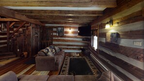 Ein rustikales Holzhaus-Interieur mit einer Couch, einem Teppich und Holzwänden.