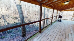 Eine Holterrasse mit Metallgeländer, einem Gasherd und einem Stuhl.