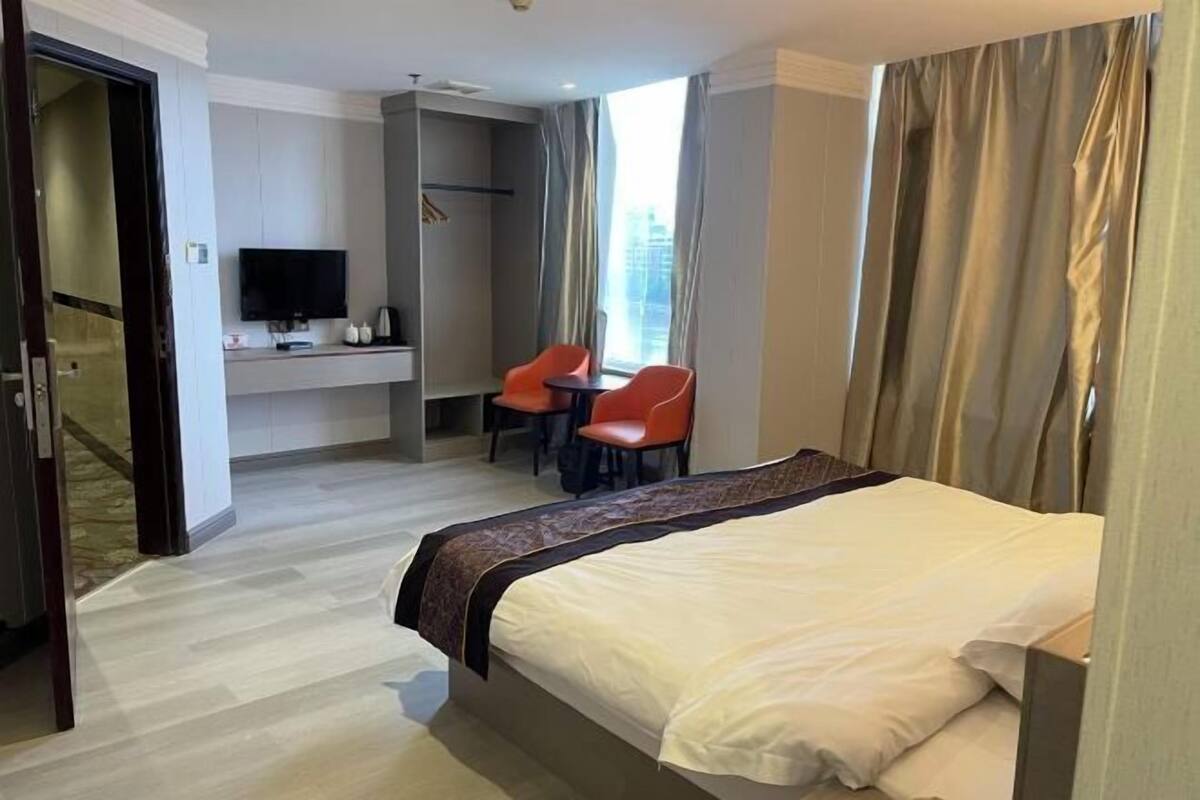 A hotel room with a bed, a TV, a desk, and two chairs.