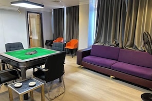 A room with a pool table, a purple sofa, and a billiards table. - United Star Hotel (Kaiping)