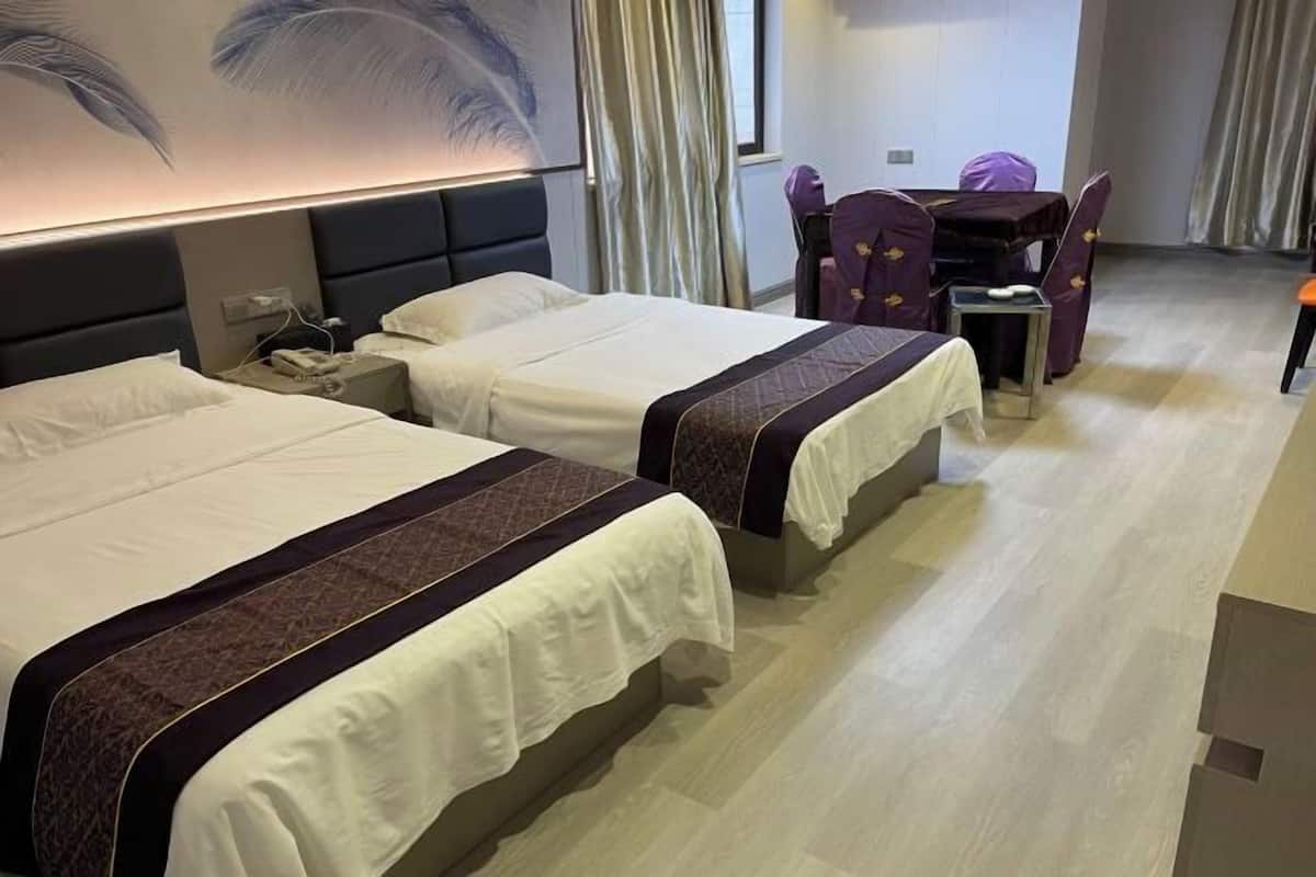 A hotel room with two beds, a desk, and a chair.