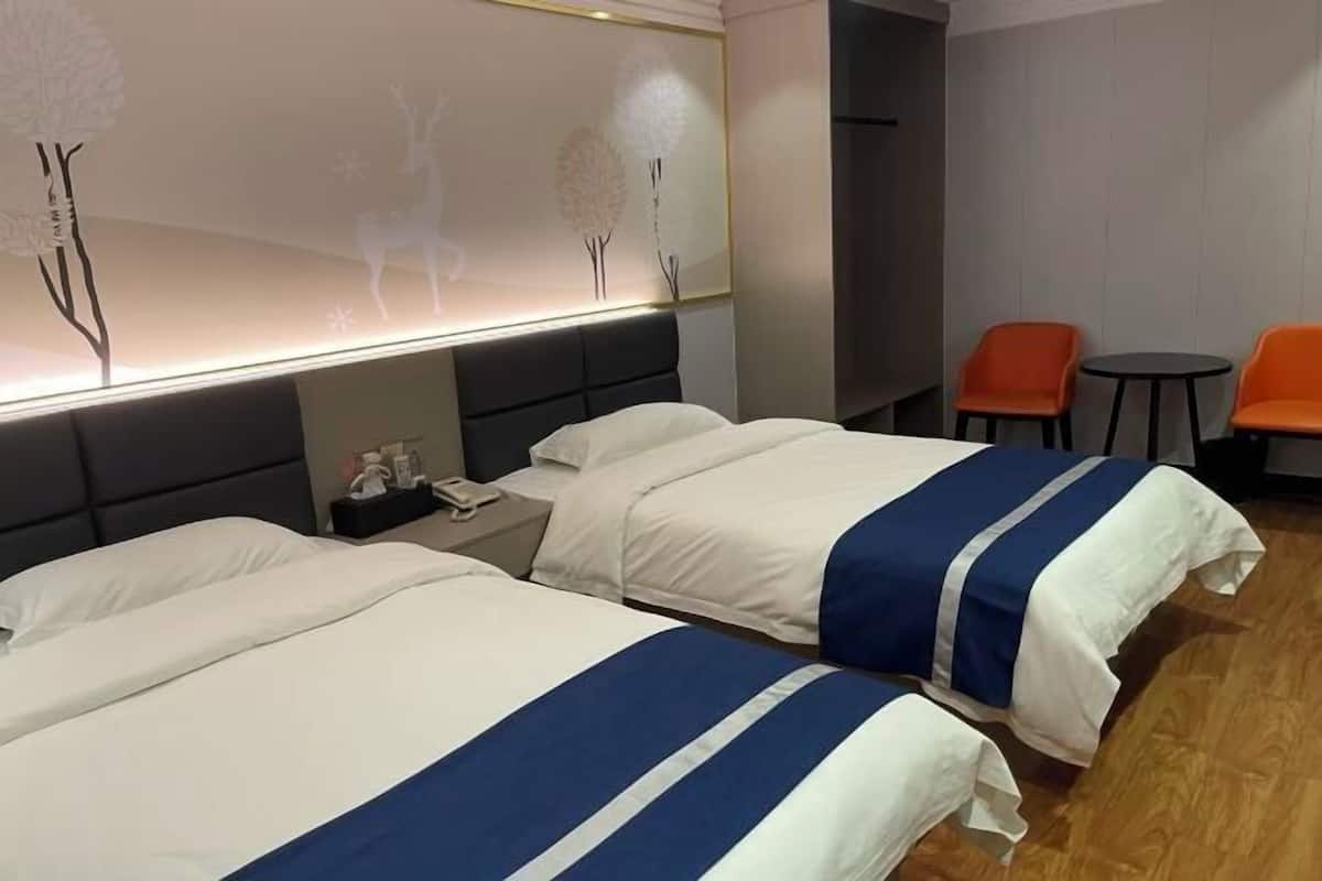 A hotel room with two beds, a nightstand, a desk, and a seating area with chairs and a table.
