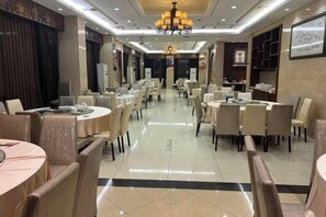 A hotel dining area with round tables and chairs, a chandelier, and a clean, tiled floor. - United Star Hotel (Kaiping)