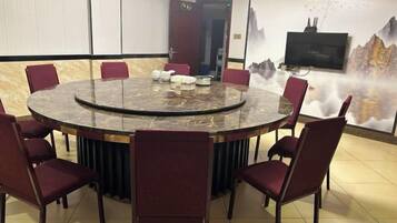 Una sala de conferencias con una mesa redonda, ocho sillas y un televisor en la pared.