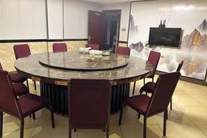 A conference room with a round table, eight chairs, and a television on the wall. - United Star Hotel (Kaiping)