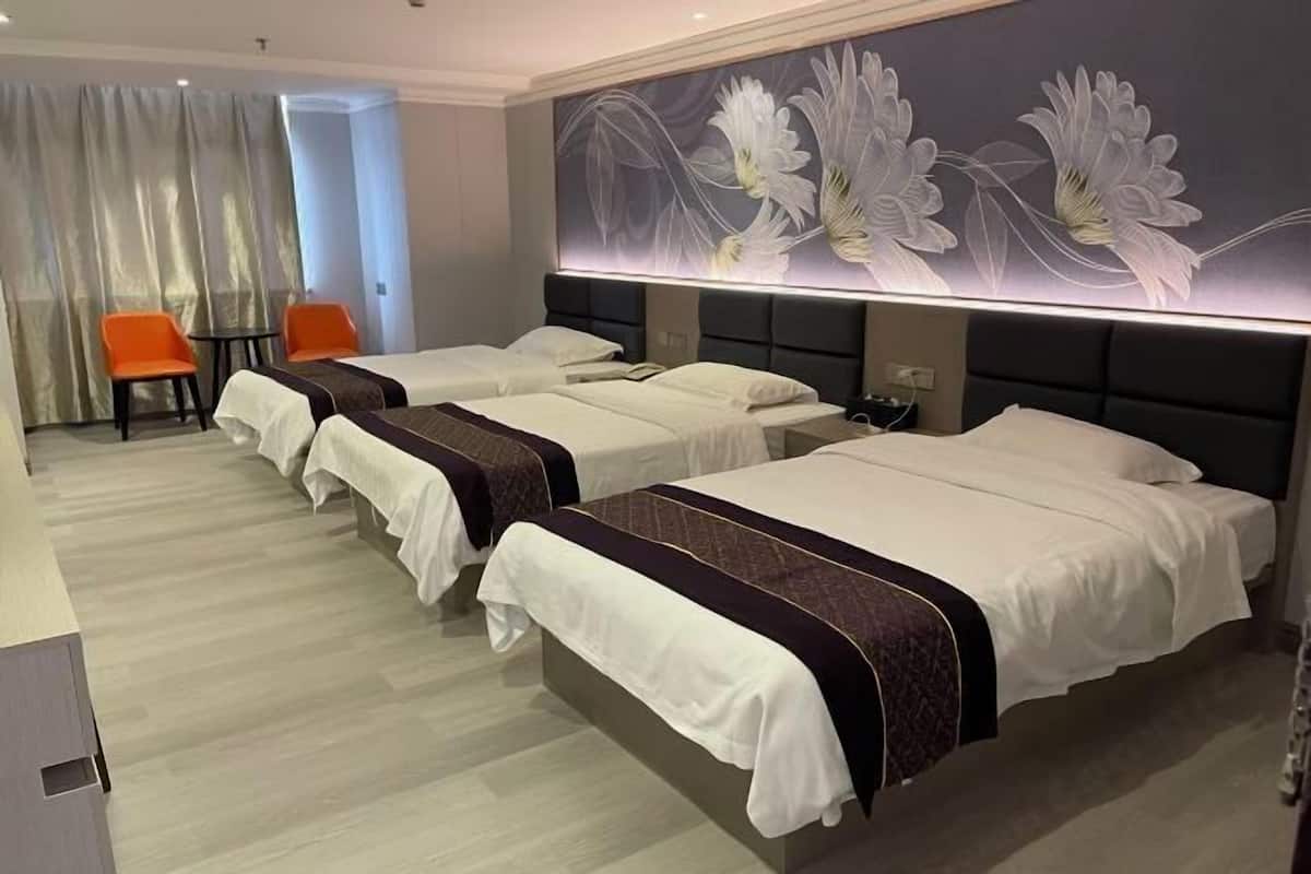 A hotel room with three beds, a desk, and a chair.