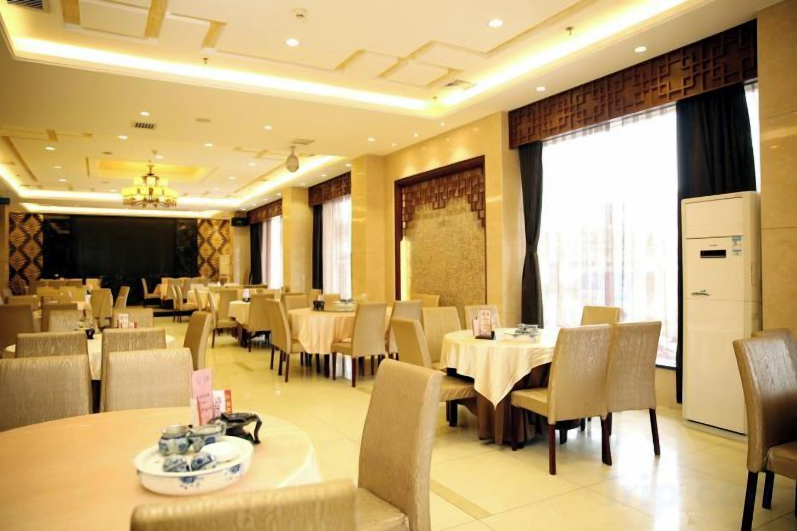 Un comedor de hotel con mesas redondas, sillas y un escenario.