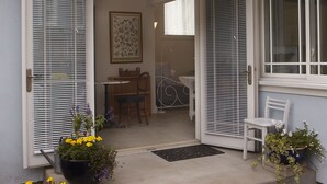 A house with a covered porch, a dining area, and a bedroom visible through an open door. - Brand New Cottage In Great Berkeley Neighborhood.  (Berkeley)
