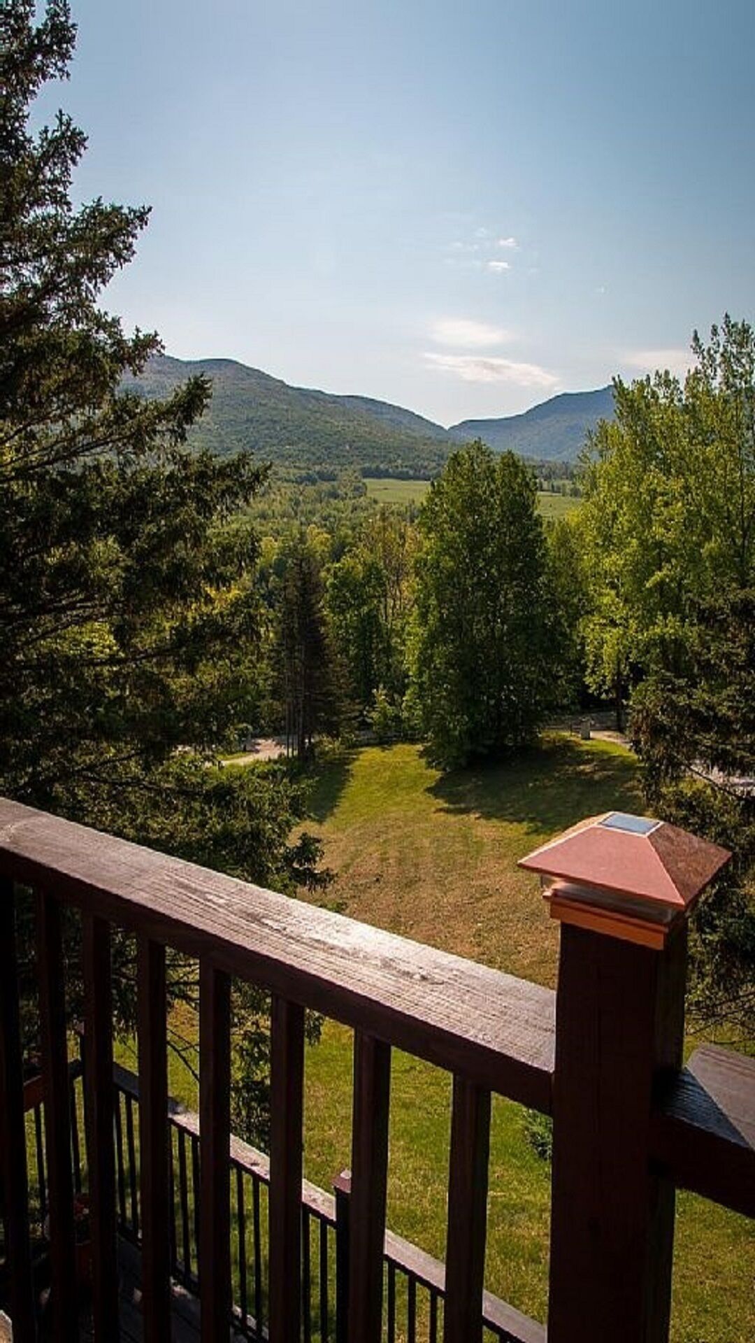 A wooden deck with a view of a grassy landscape and trees.