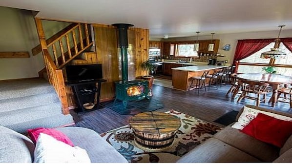 A cozy living room with a fireplace, a sofa, a coffee table, and a staircase leading to another level.
