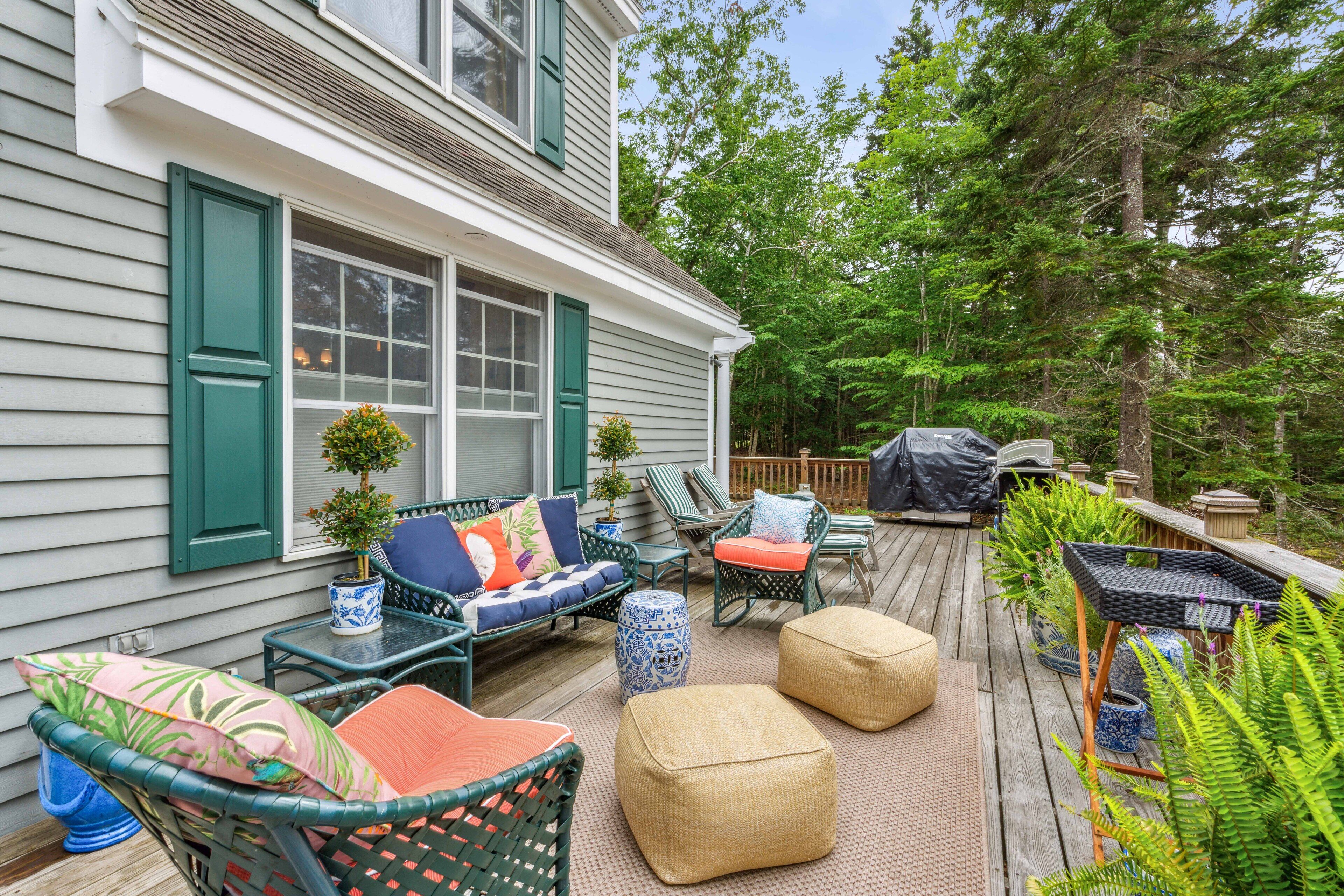 Une terrasse couverte, aménagée avec des meubles en osier, une petite table ronde et un espace barbecue.