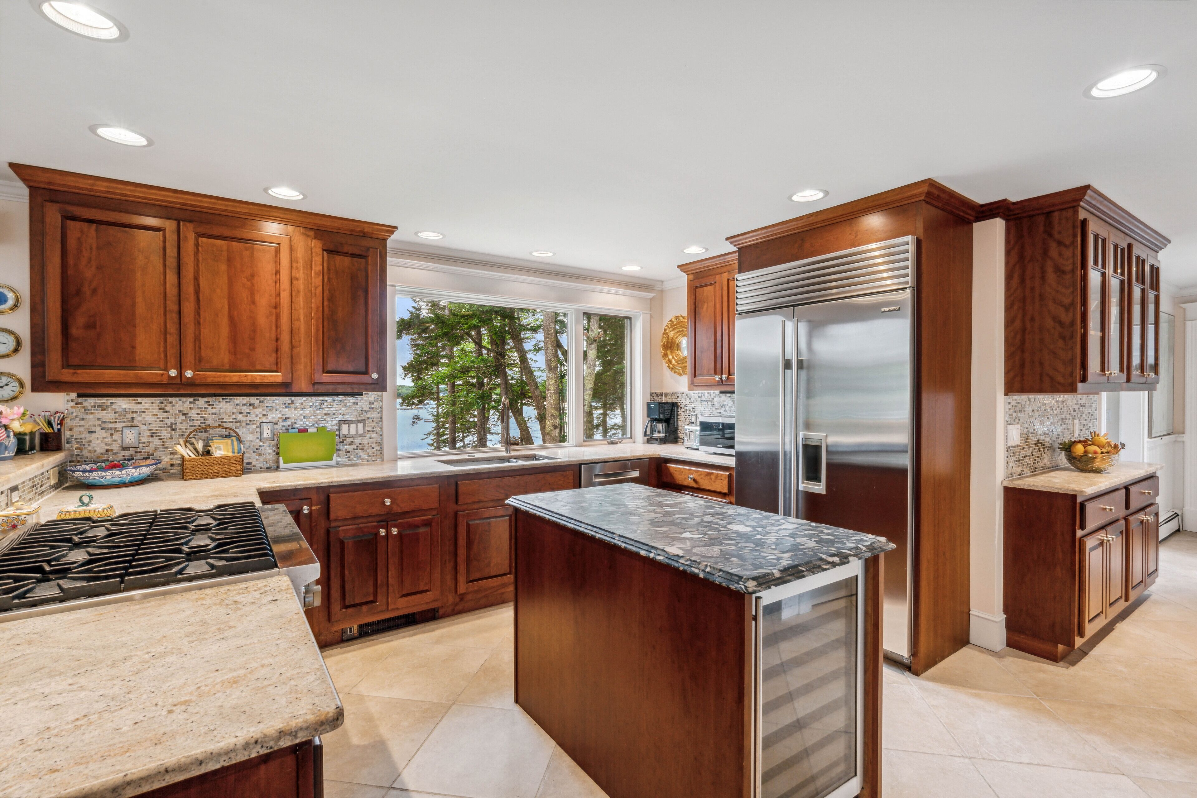 A kitchen with wooden cabinets, a stainless steel refrigerator, and a granite countertop.