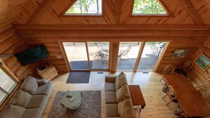 L’intérieur d’un chalet accueillant, avec un plafond en bois, un canapé, une table basse et une table à manger.