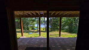 Une vue à travers une fenêtre à cadre en bois, donnant sur un lac et la végétation environnante.