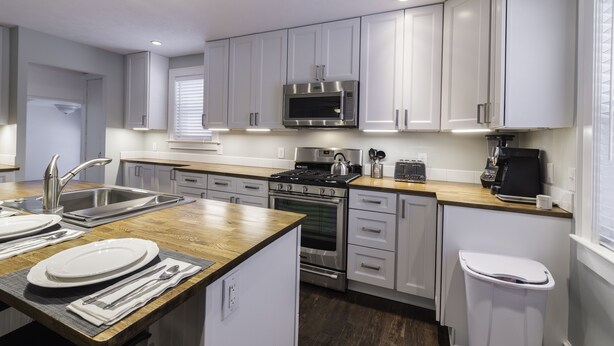 A modern kitchen with white cabinets, stainless steel appliances, and a wooden countertop. - JUST REMODELED top to bottom -  master bed/bath on main floor! (Cleveland Heights)