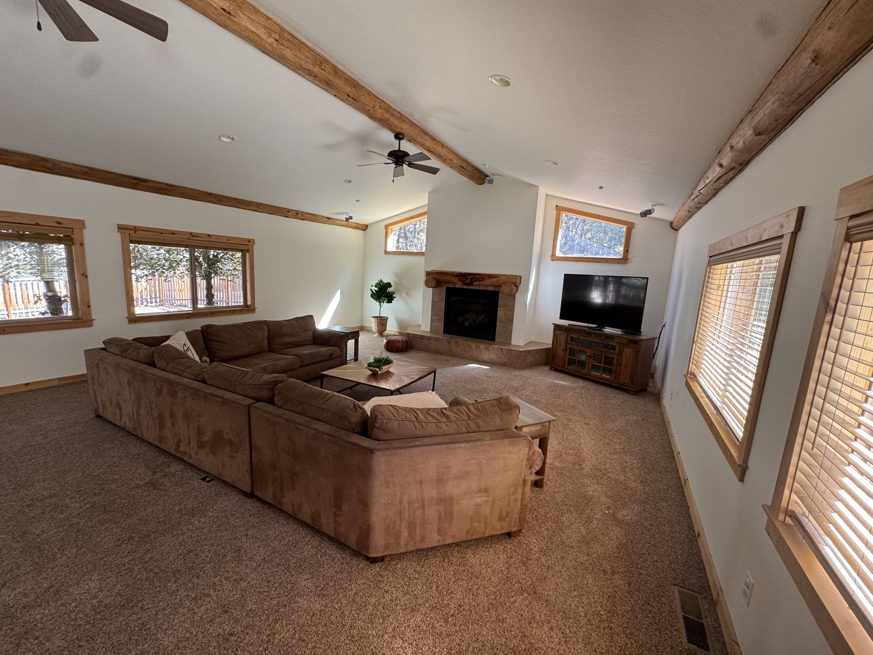 A living room with a sectional sofa, a fireplace, a television, and a ceiling fan.