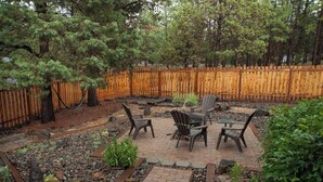 Un espace patio agrémenté d’une clôture en bois, d’une table avec des chaises et d’un jardin avec des rochers et des plantes.