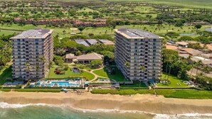 Ett semesterhotell med två höga byggnader, en pool och en strand.