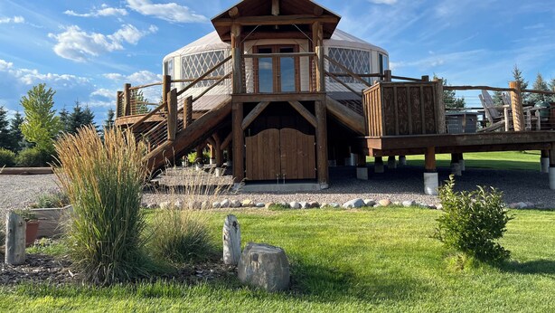 A wooden cabin with a large central dome, wooden stairs, and a deck. - Luxury Yurt bordering Flathead Lake (Somers)