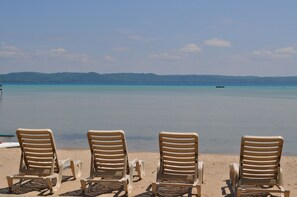 A beach with three sun loungers facing the ocean, a clear sky, and a distant boat. - Beautiful On Big Glen Lake Sandy Beach! (Glen Arbor)