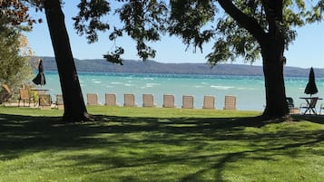 Relax on the lakeside lawn with a serene view of the lake, surrounded by lounge chairs and shaded by umbrellas.