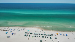 Luchtbeeld van een strand met rijen strandparasols en ligbedden.
