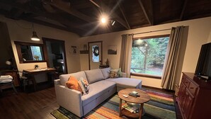 Un salon confortable avec un canapé, une table basse et une vue sur l ’extérieur grâce à une grande fenêtre.