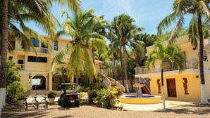A resort with a pool, palm trees, and a jeep. - Large 5+ Bedroom Oceanfront w/ Pier and Pool (Placencia)