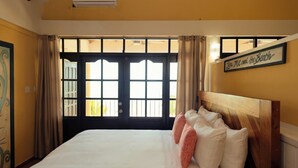A bedroom with a large bed, a wooden headboard, and a view through a window with curtains. - Large 5+ Bedroom Oceanfront w/ Pier and Pool (Placencia)