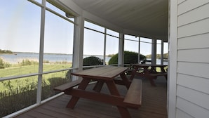 Un espace extérieur abrité, équipé de tables de pique-nique et offrant une vue sur un lac.