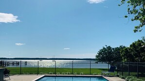 Une piscine rectangulaire offrant une vue dégagée sur une étendue d’eau, au-delà d’une clôture en métal noir.