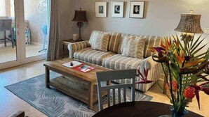 Ein Wohnzimmer mit Sofa, Couchtisch und Lampe. An der Wand hängen drei gerahmte Bilder.