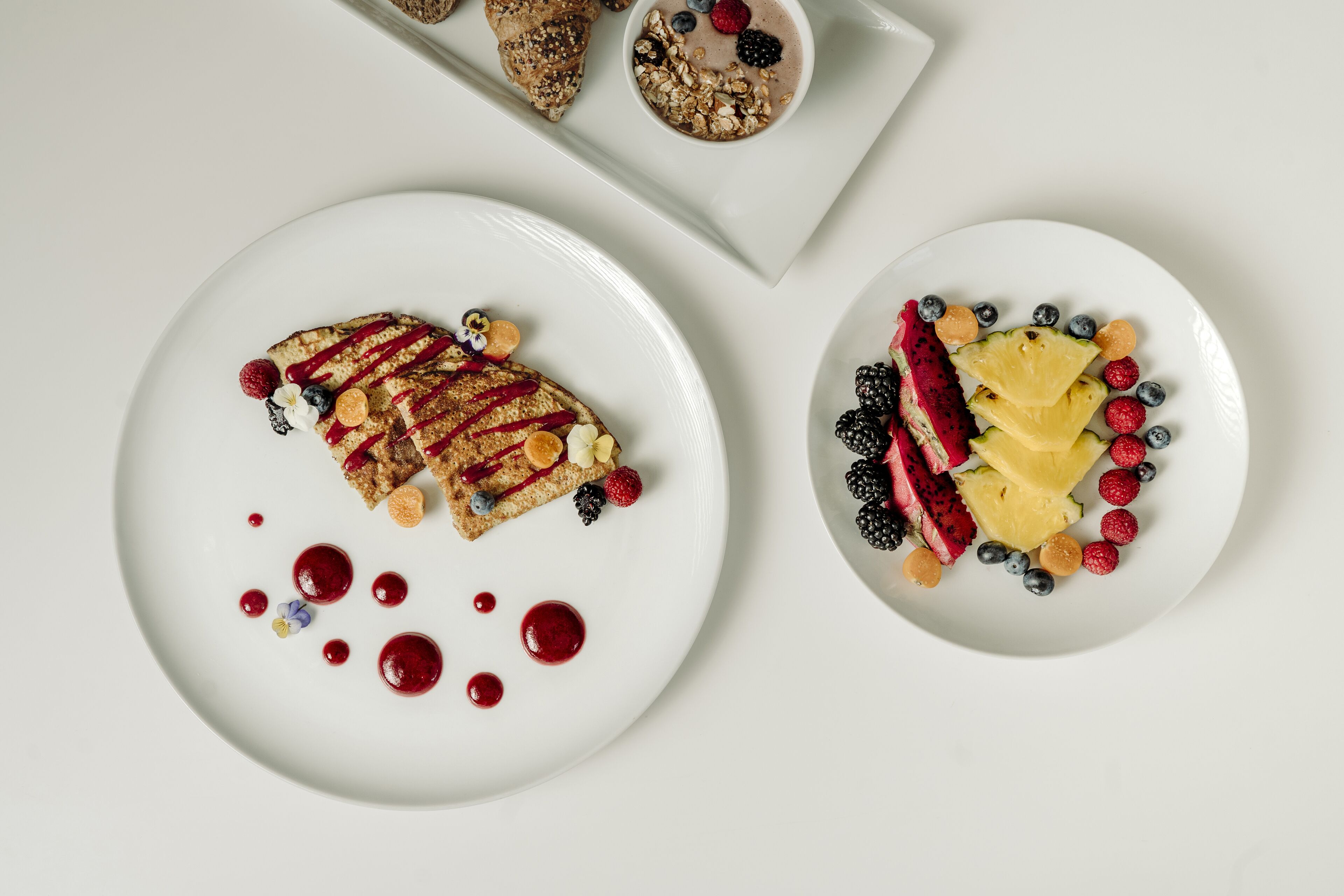 Zwei weiße Teller mit verschiedenen Früchten und Desserts.