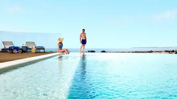 Een binnenzwembad, een buitenzwembad, ligstoelen bij het zwembad