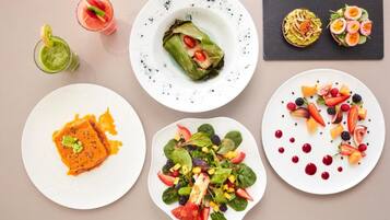 Variedad de platos, incluyendo un plato de salmón, una ensalada y dos bebidas a base de fruta.
