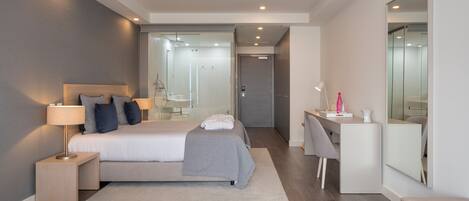 A modern bedroom with a bed, bedside table, lamp, and a desk with a chair.