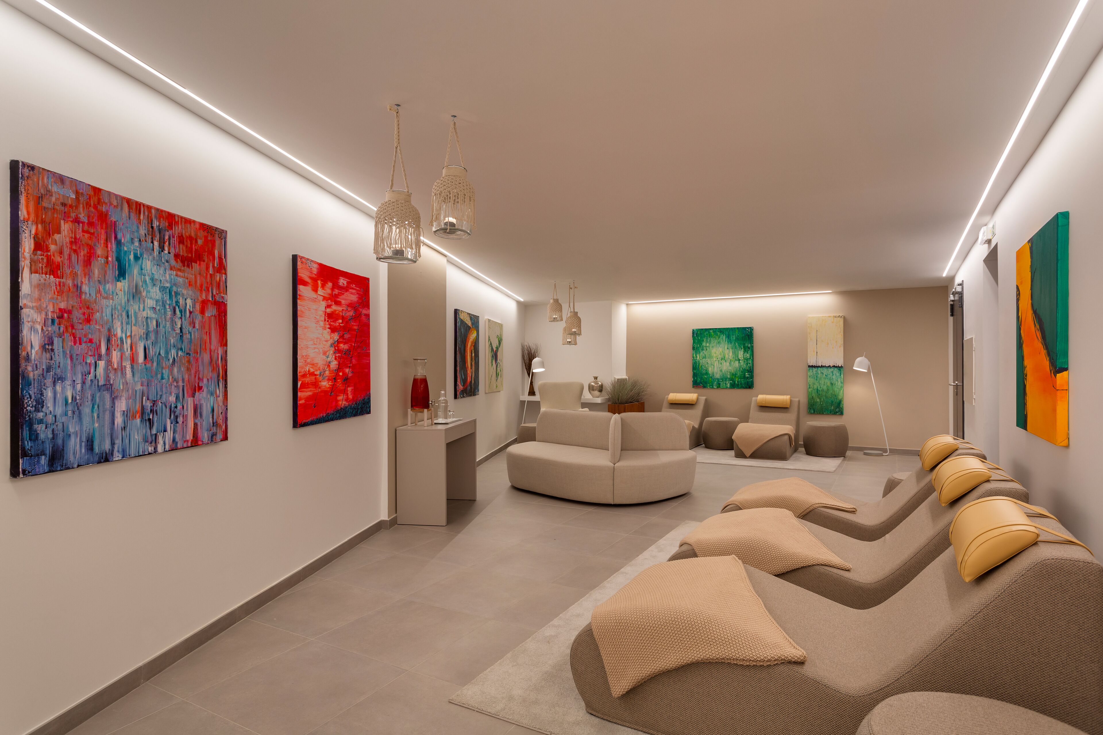 A modern spa room with a curved seating area, artwork on the walls, and ambient lighting.