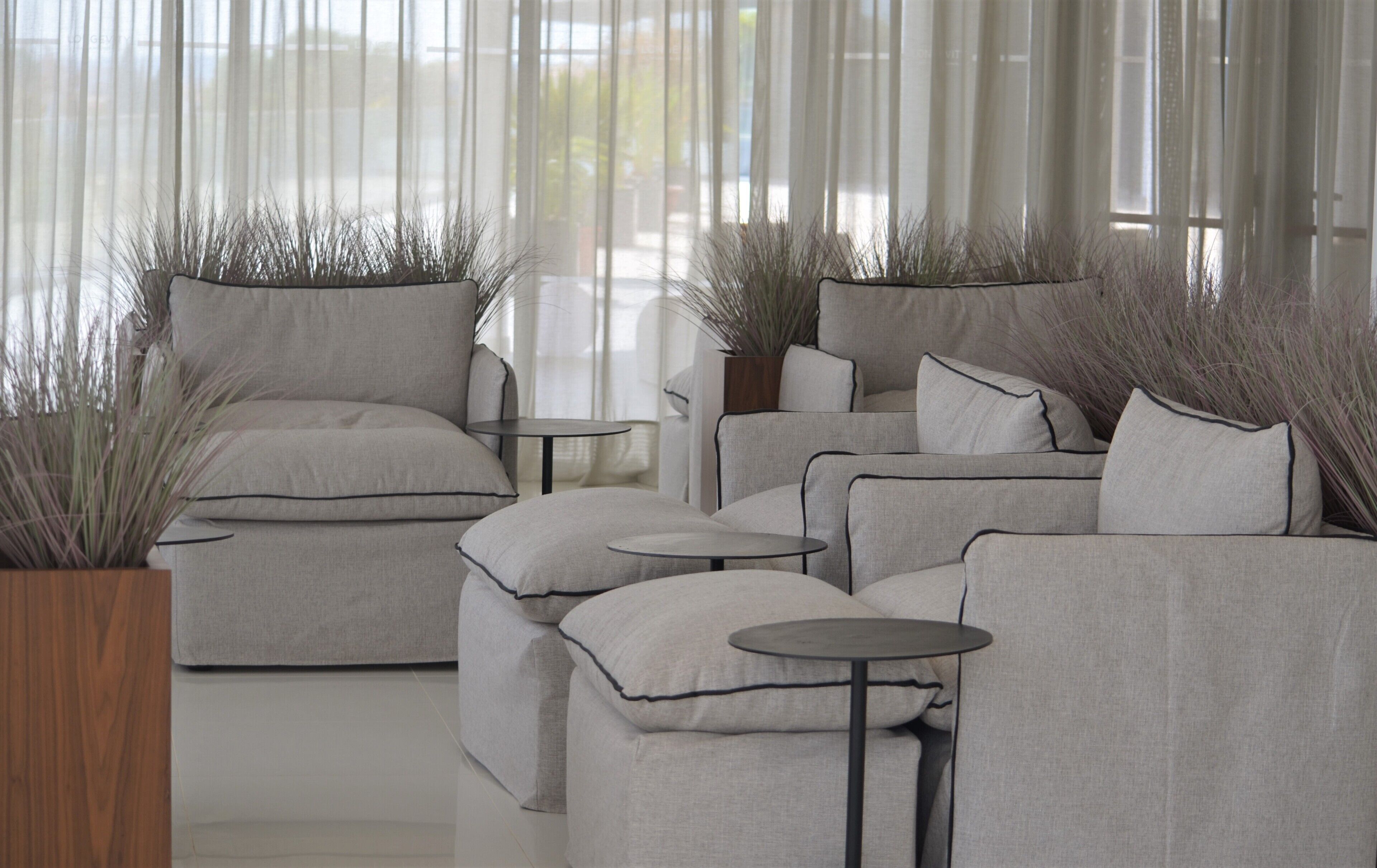 A modern living room with a sofa set, two round tables, and decorative plants.