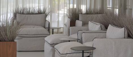 A modern living room with a sofa set, two round tables, and decorative plants.