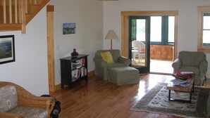 A spacious living room with a wooden staircase, a sofa, a small table, and a bookshelf.