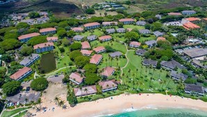Vue aérienne d’un complexe hôtelier comprenant plusieurs bâtiments, un terrain de golf et une plage.