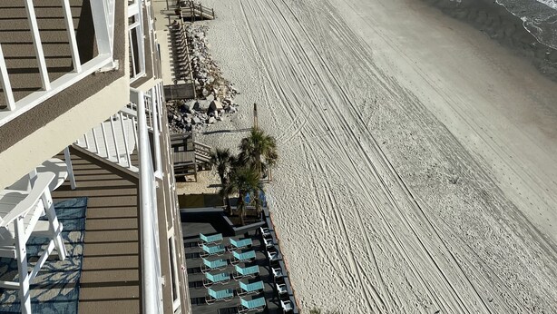 Ein Hotel direkt am Strand mit Pool, Liegestühlen und Blick auf das Meer.