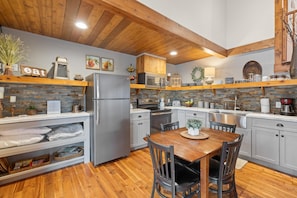 A modern kitchen with wooden beams, a stone backsplash, and a central island.