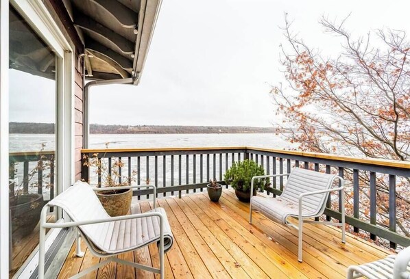 Enjoy the serene view of the water from this deck, featuring a comfortable seating area with a potted plant.
