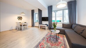 A modern living room with a sofa, dining table, and TV. - ShortStayPoland Środkowa - B49 (Warsaw)