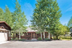 A lodge with a wooden exterior, a front porch, and a garage. - SPECIAL RATES Pet Friendly Log Cabin, Sleeps 8, Hot Tub, Fishing & Skiing Galore (Manhattan)