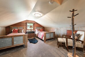 A cozy attic bedroom with two wooden beds, a chair, a coat rack, and a fur rug. - SPECIAL RATES Pet Friendly Log Cabin, Sleeps 8, Hot Tub, Fishing & Skiing Galore (Manhattan)