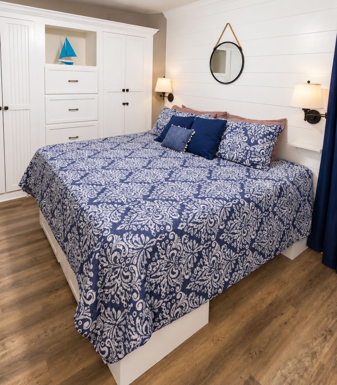 A bedroom with a large bed, white wardrobe, and a mirror on the wall.