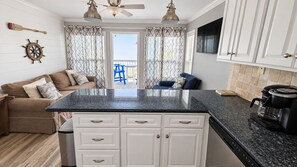 A compact kitchen with white cabinets, a granite countertop, and a coffee maker.