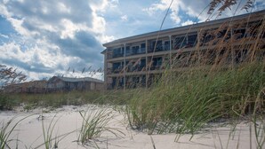 A beachfront hotel with multiple balconies and a sandy beach in the foreground.